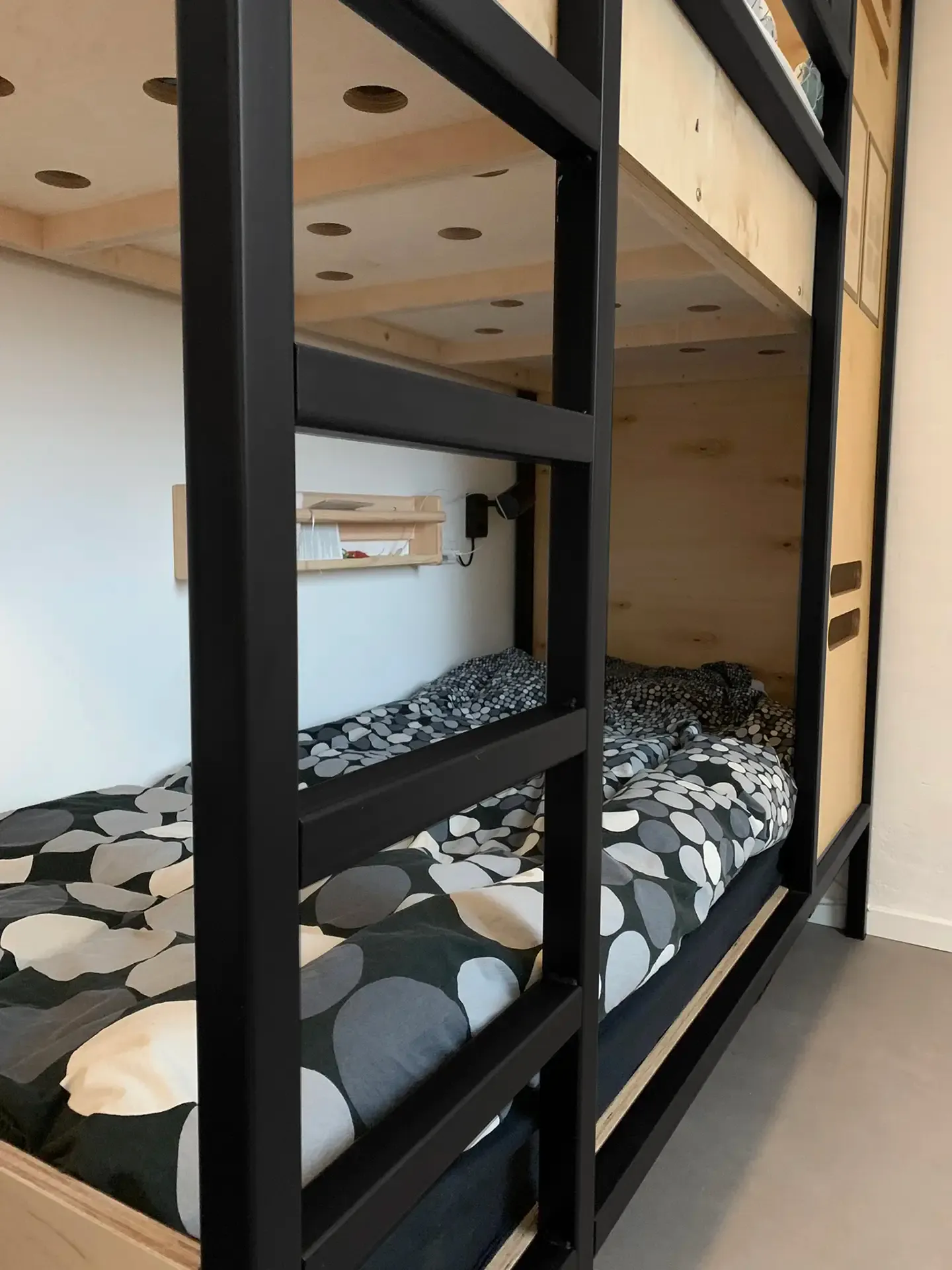 Double bunk beds with black metal frames and wood cladding, tailored for intensive daily use in student housing.